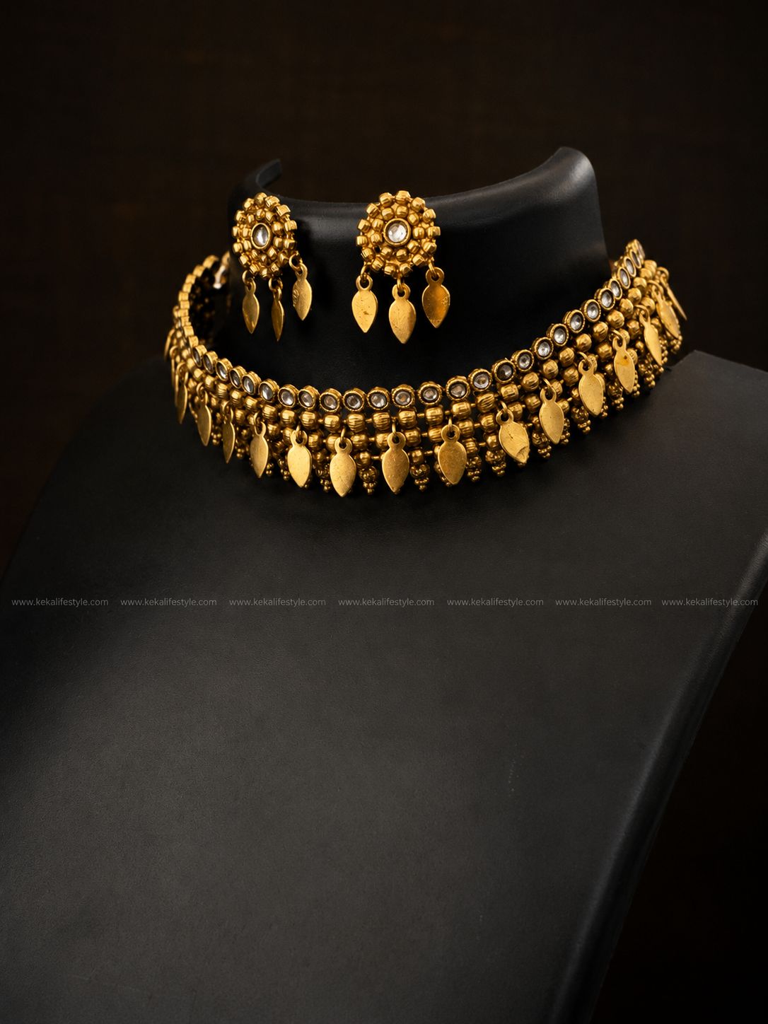 NGN0249 - Premium quality llakkathali design necklace with antique gold finish, white stone detailing and traditional leaf danglings. Comes with matching earrings